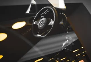 Gros plan sur un volant Mercedes dans un habitacle sombre.